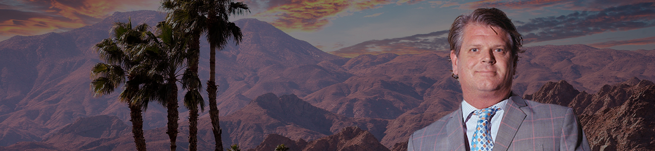 Christopher Donald Hewitt is standing with palms and a mountain in the background.